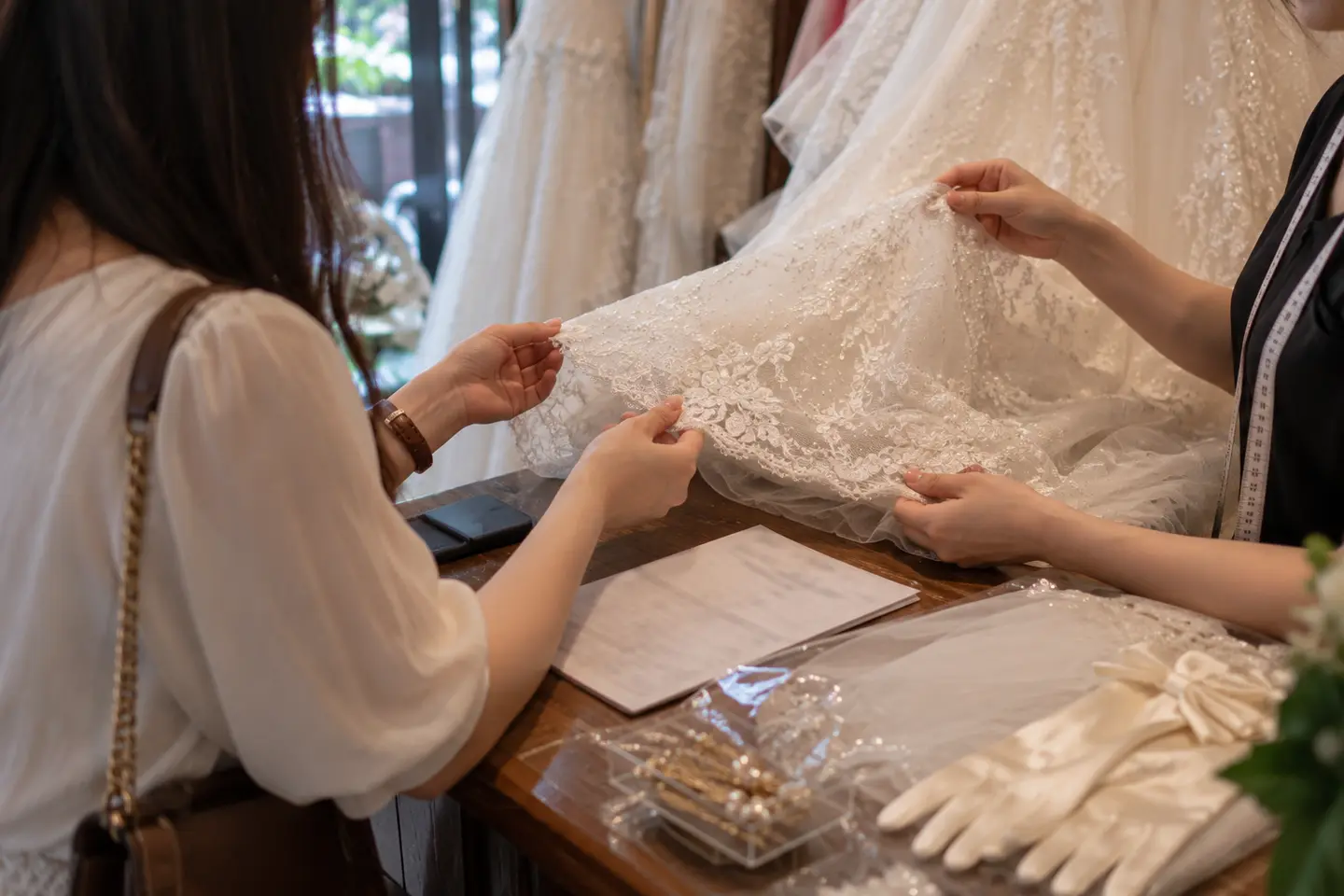 Nhân viên tiệm và cô dâu kiểm tra gấu váy cưới thuê trước khi nhận
